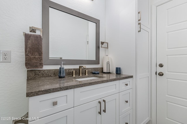 bathroom featuring a textured wall and vanity