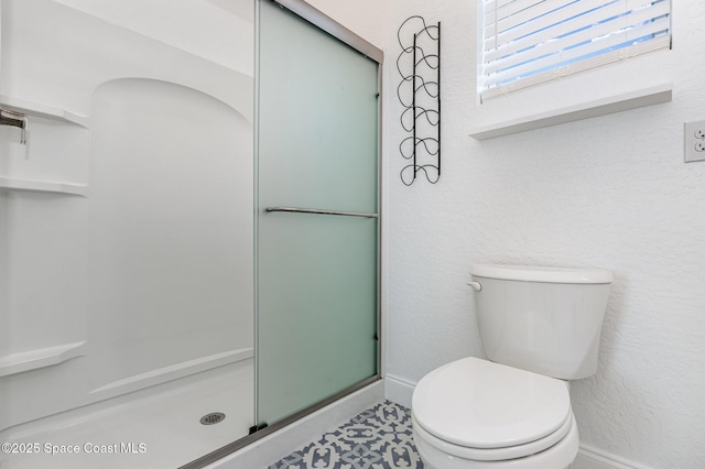 bathroom featuring baseboards, a textured wall, toilet, and an enclosed shower