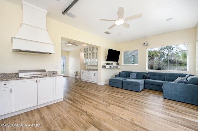 unfurnished living room with a ceiling fan, light wood-style flooring, visible vents, and baseboards