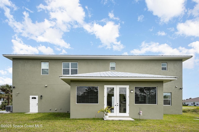 rear view of property featuring a yard, central AC unit, stucco siding, and french doors