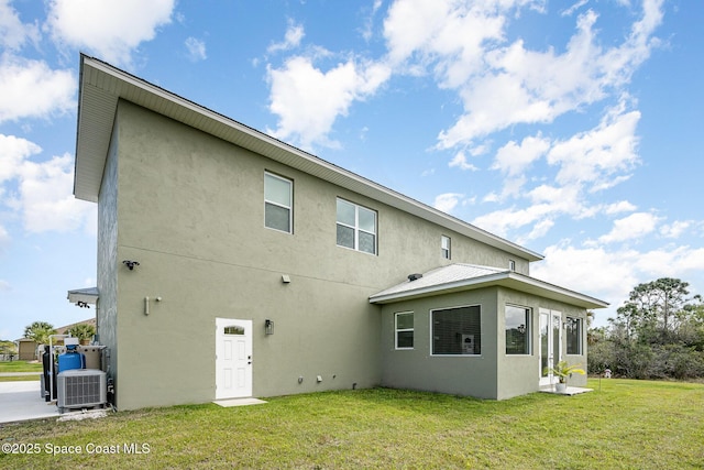 back of house with a yard, central AC, and stucco siding