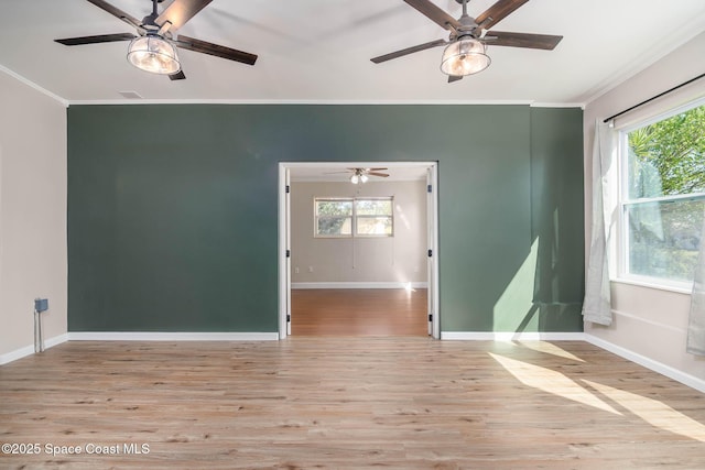 empty room with a ceiling fan, crown molding, baseboards, and wood finished floors