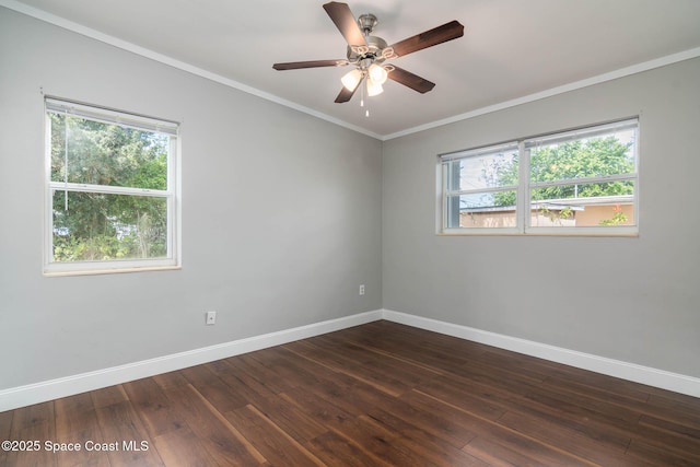 empty room with a wealth of natural light, baseboards, dark wood-style floors, and crown molding