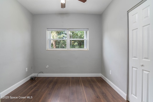 empty room with dark wood-type flooring, a ceiling fan, and baseboards