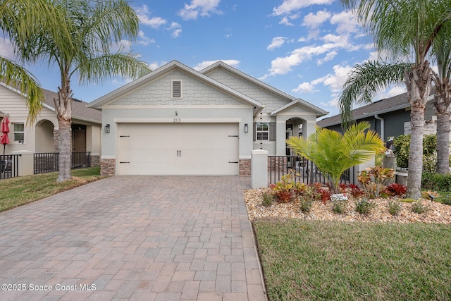 craftsman-style home featuring decorative driveway, an attached garage, fence, and stucco siding