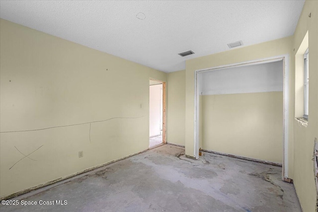 unfurnished bedroom with a textured ceiling, visible vents, a closet, and unfinished concrete floors