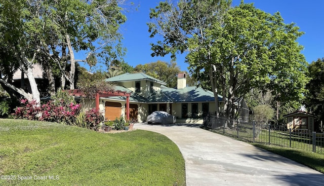 view of front of property featuring concrete driveway, a chimney, fence, a front lawn, and stucco siding