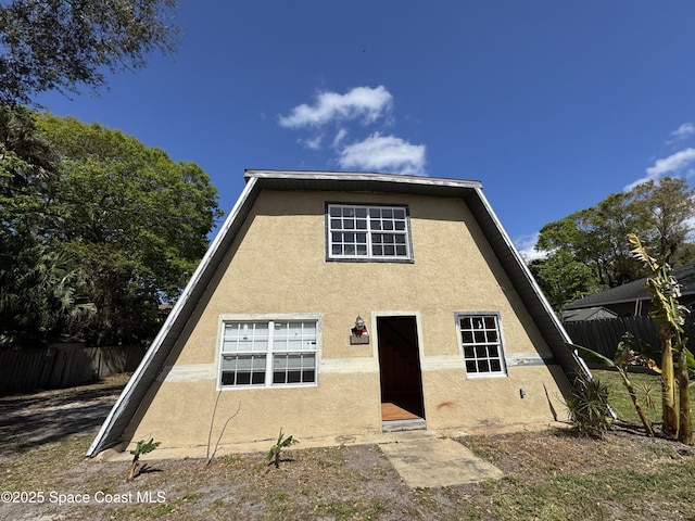 back of house featuring fence and stucco siding