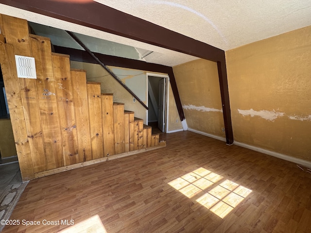 interior space with a textured ceiling, stairs, baseboards, and wood finished floors