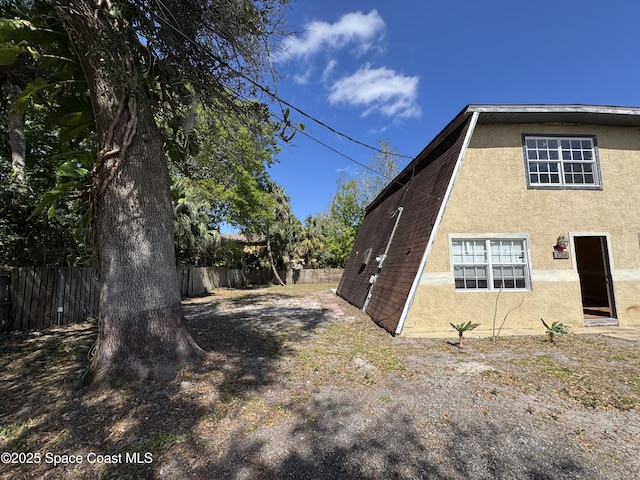 view of side of home featuring fence and stucco siding