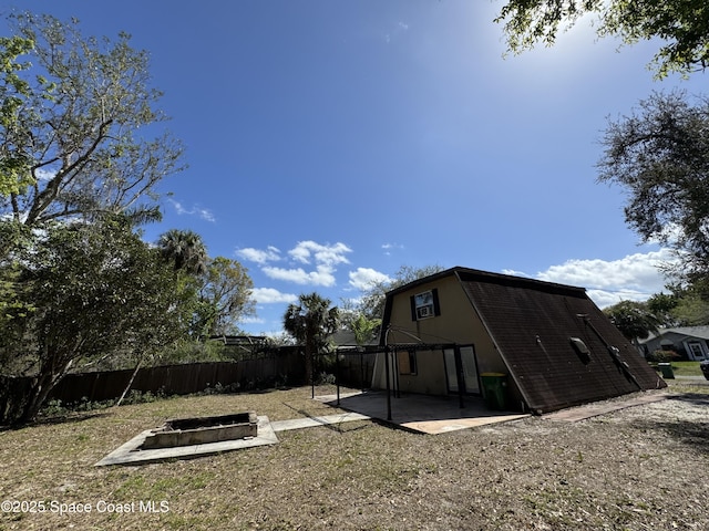 exterior space featuring an outdoor fire pit, a patio area, fence, and a gambrel roof