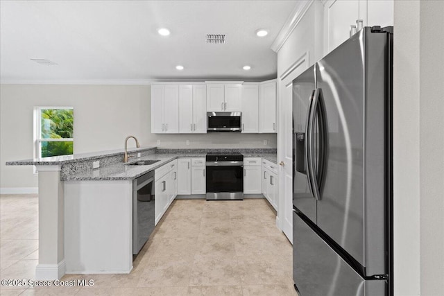 kitchen featuring stainless steel appliances, white cabinetry, a sink, light stone countertops, and a peninsula