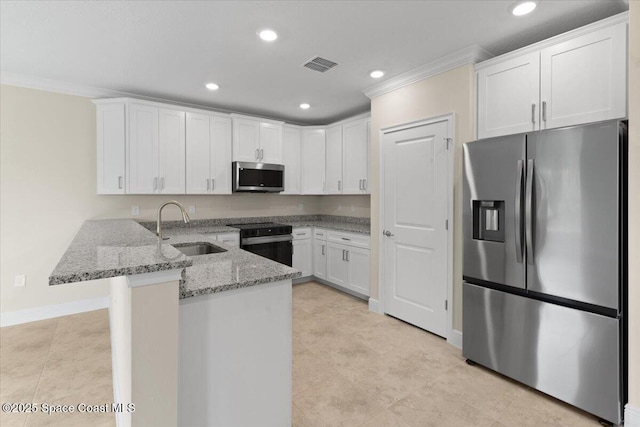 kitchen with a peninsula, white cabinetry, stainless steel appliances, and a sink