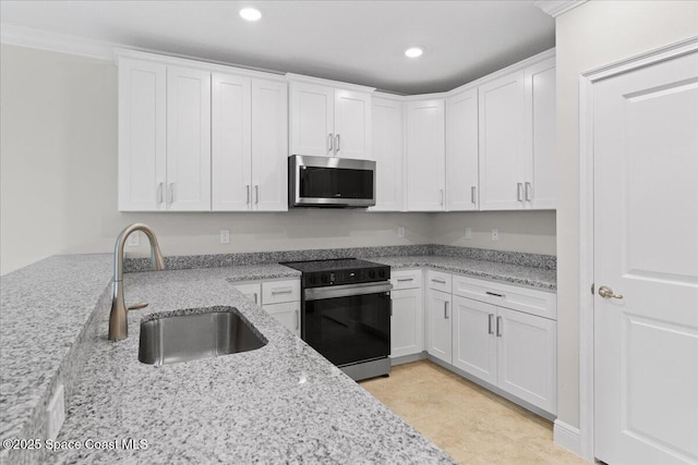 kitchen with range with electric stovetop, a sink, white cabinetry, light stone countertops, and stainless steel microwave