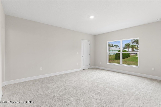 unfurnished room with light colored carpet and baseboards