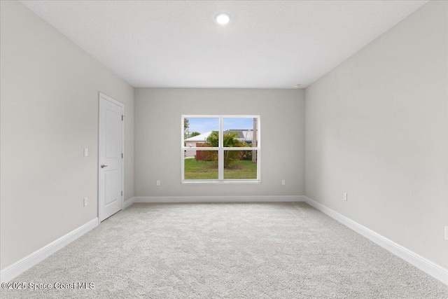 unfurnished room featuring light carpet and baseboards