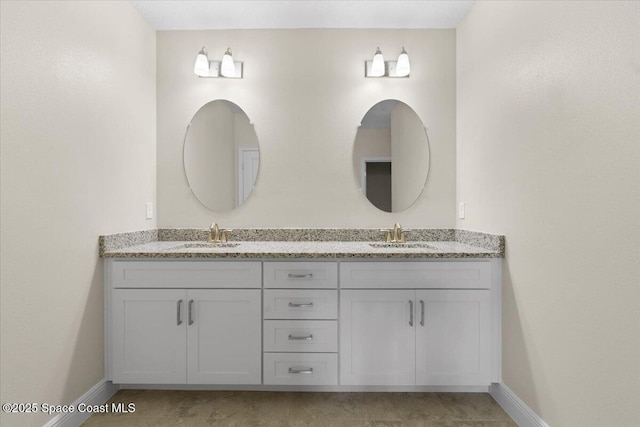 full bath featuring double vanity, baseboards, and a sink