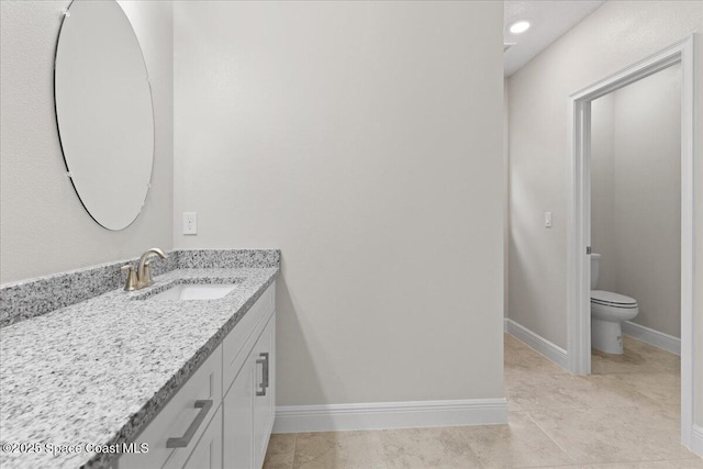 bathroom with toilet, vanity, and baseboards