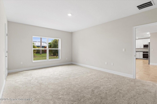 unfurnished room featuring recessed lighting, light colored carpet, visible vents, a textured ceiling, and baseboards