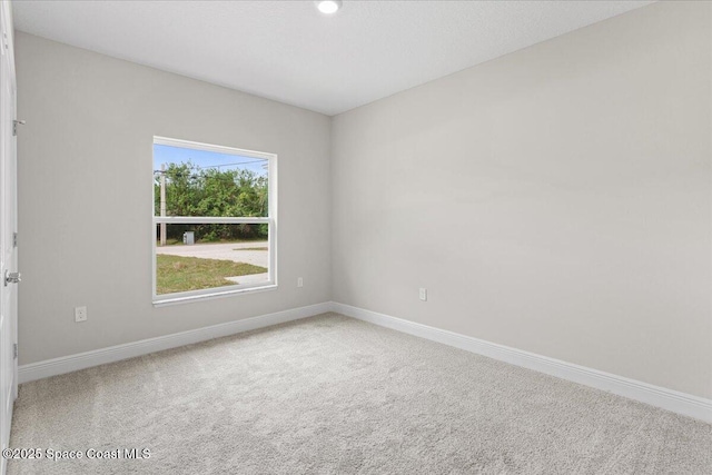 empty room featuring carpet and baseboards