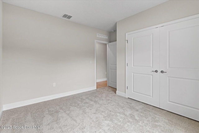 unfurnished bedroom with baseboards, a closet, visible vents, and carpet flooring