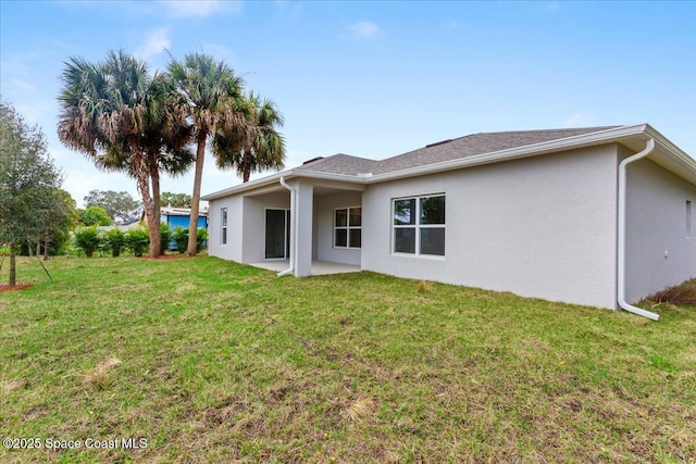 rear view of property with a lawn and stucco siding