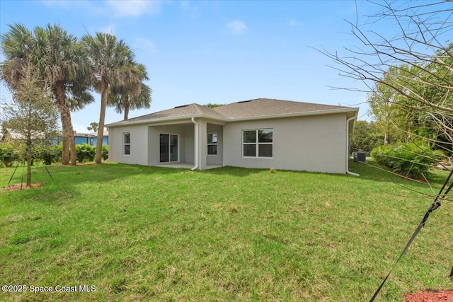 back of property featuring a lawn and stucco siding