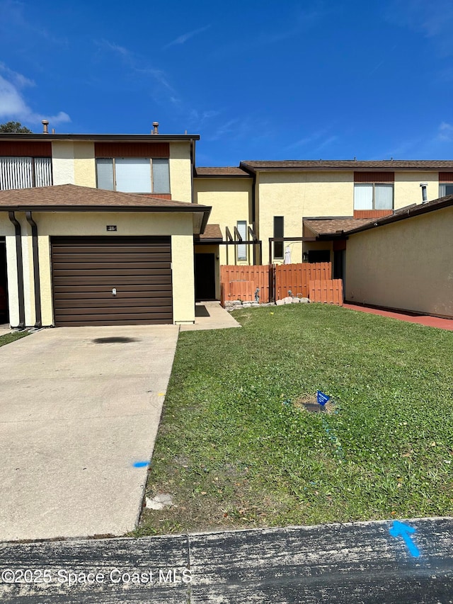 view of front facade with a garage, fence, driveway, stucco siding, and a front lawn