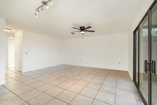 empty room with light tile patterned floors, baseboards, and a ceiling fan