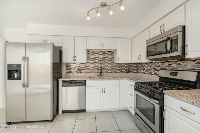 kitchen featuring backsplash, light stone counters, stainless steel appliances, white cabinetry, and a sink