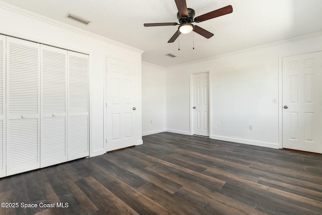 unfurnished bedroom with visible vents, crown molding, and dark wood-style flooring
