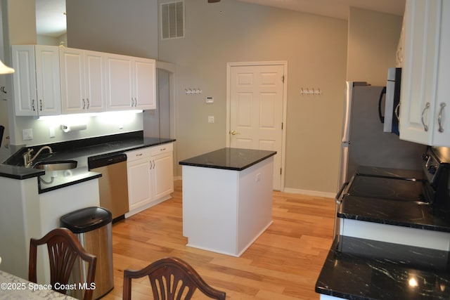 kitchen with light wood finished floors, visible vents, dishwasher, white cabinets, and a sink