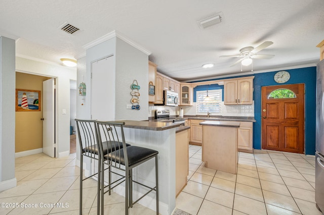 kitchen featuring light tile patterned flooring, visible vents, appliances with stainless steel finishes, light brown cabinetry, and dark countertops