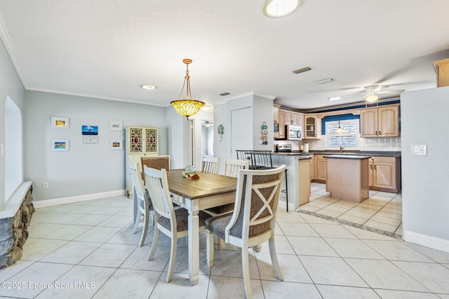 dining area with light tile patterned floors, baseboards, visible vents, and crown molding