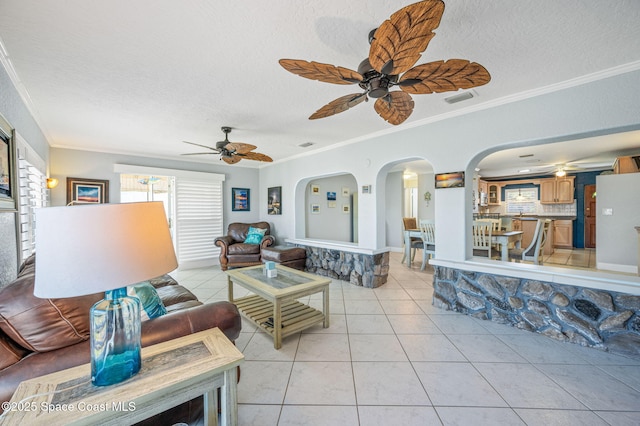 living area featuring arched walkways, crown molding, visible vents, light tile patterned flooring, and a textured ceiling