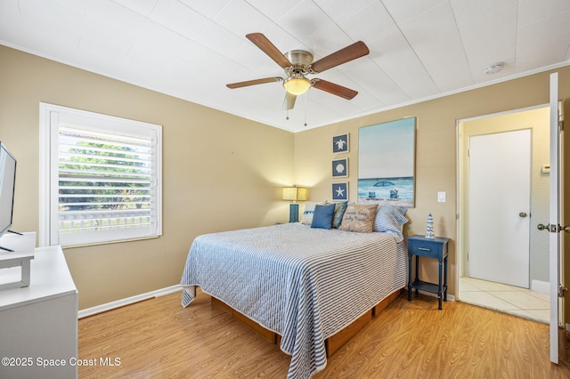 bedroom featuring a ceiling fan, baseboards, crown molding, and light wood finished floors