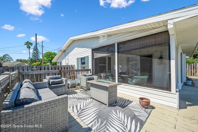 wooden deck featuring a sunroom, fence, and an outdoor living space