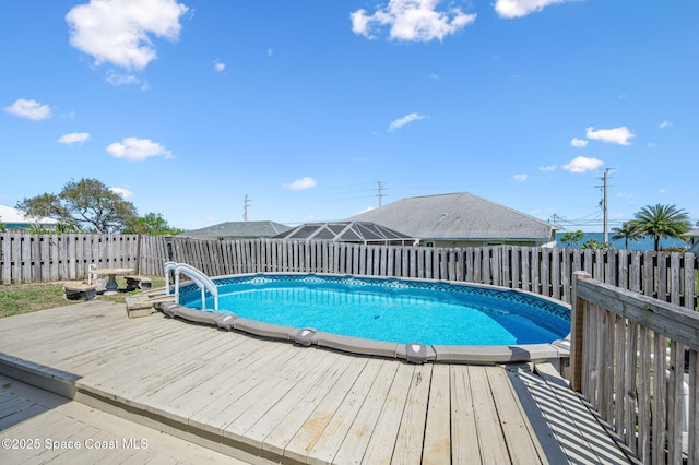 view of swimming pool with a wooden deck, a fenced in pool, and fence