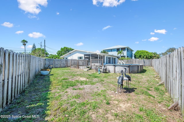 view of yard with a sunroom, a fenced backyard, and a fenced in pool