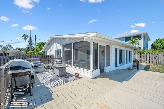 wooden terrace with a sunroom, outdoor lounge area, fence, and grilling area