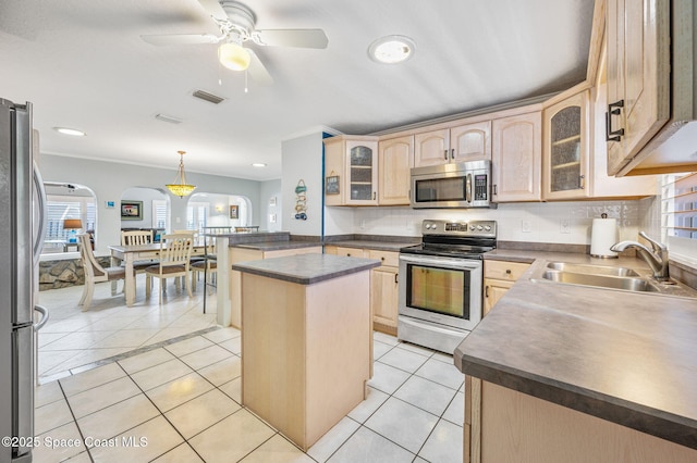 kitchen with arched walkways, light tile patterned floors, appliances with stainless steel finishes, light brown cabinets, and a sink