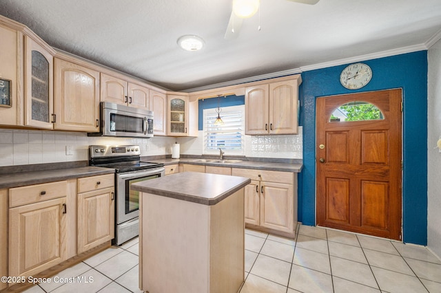 kitchen featuring dark countertops, light brown cabinets, stainless steel appliances, and a sink