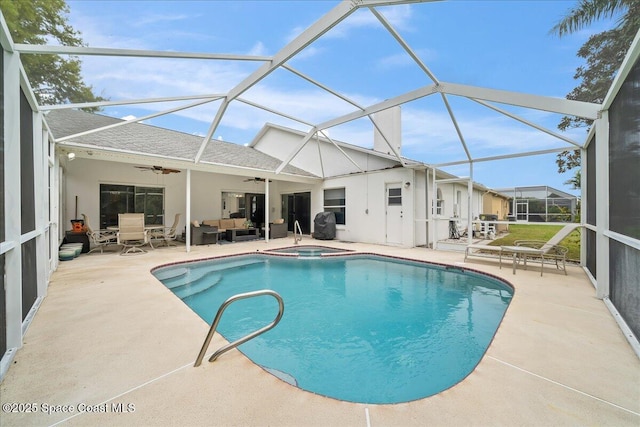 view of pool featuring a pool with connected hot tub, ceiling fan, glass enclosure, outdoor lounge area, and a patio area