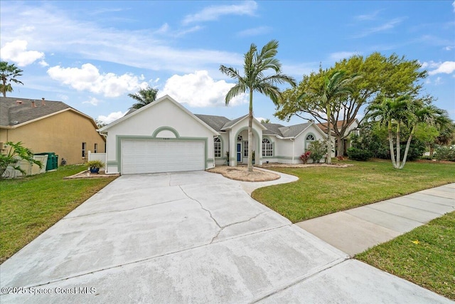 view of front of property with stucco siding, an attached garage, concrete driveway, and a front lawn