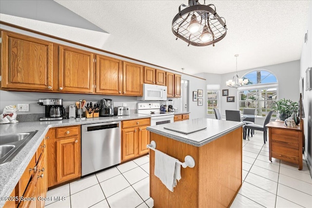 kitchen featuring a textured ceiling, a center island, white appliances, brown cabinetry, and light tile patterned floors