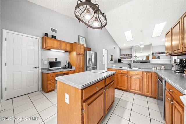 kitchen with a sink, a center island, stainless steel appliances, a skylight, and light tile patterned floors