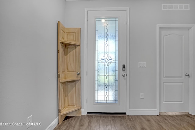 doorway with visible vents, baseboards, and wood finished floors