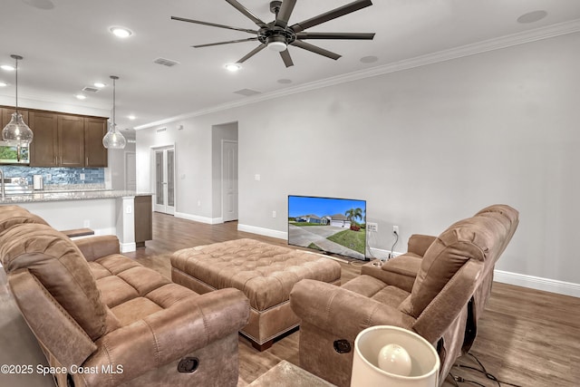 living room featuring crown molding, baseboards, and wood finished floors