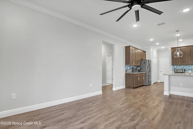 unfurnished living room featuring ornamental molding, wood finished floors, and baseboards