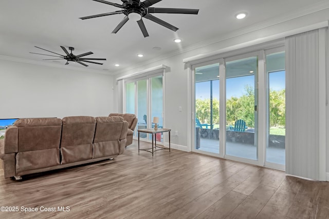 living area featuring recessed lighting, baseboards, crown molding, and wood finished floors